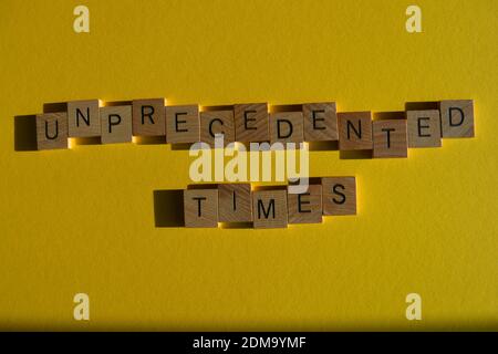 Unprecented Times, phrase in wooden alphabet letters isolated on yellow background Stock Photo