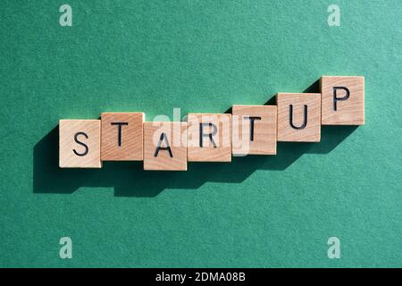 Startup, Wort in Holzbuchstaben isoliert auf grünem Hintergrund Stockfoto