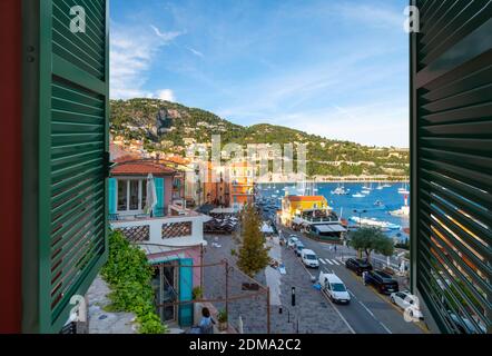 Scenic view through an open window of the colorful town, bay and marina of Villefranche Sur Mer, on the French Riviera coast of Southern France. Stock Photo