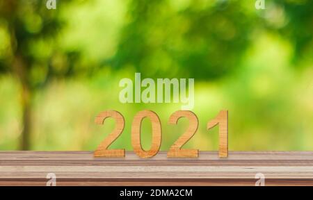 Wooden number 2021 on wood table over green nature background. Concept of beginning the new year Stockfoto