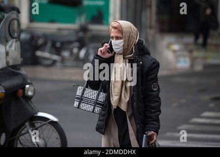 Teheran, Iran. Dezember 2020. Eine Frau mit Gesichtsmaske überquert eine Straße in Teheran, Iran, 16. Dezember 2020. Das iranische Gesundheitsministerium meldete 7,603 neue COVID-19 Fälle, was die Gesamtzahl der Infektionen auf 1,131,077 erhöht. Sie meldete auch 213 neue Todesfälle, was die Zahl der Todesopfer auf 52,883 besagte. Quelle: Ahmad Halabisaz/Xinhua/Alamy Live News Stockfoto