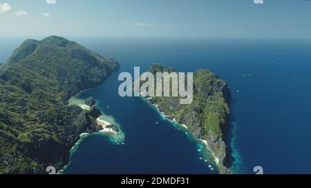 El Nido-Inseln bei blauer Meeresbucht Luftaufnahme. Grüne Berginsel mit tropischem Wald am Sandstrand. Wunderbare Seeslandschaft mit grünen Inseln des philippinischen Archipels. Drohnenaufnahme im Kino