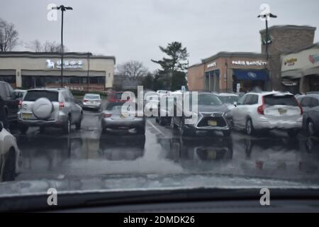 Ich habe in einem Einkaufszentrum im Regen geparkt und dabei auf die Straße geschaut Durch eine nasse Windschutzscheibe -01 Stockfoto