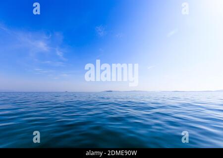 Eine kleine unbewohnte grüne Insel inmitten eines ruhigen blauen Meeres und blauen Himmels. Schöne Entspannung Hintergrund Stockfoto