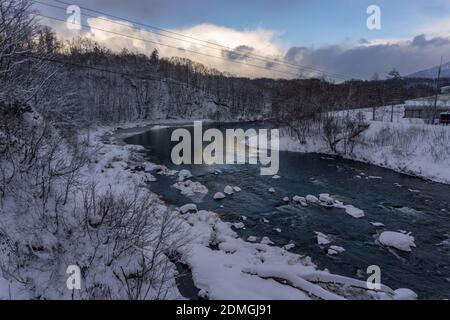 River flowing through a snow covered valley, blue sky Stock Photo