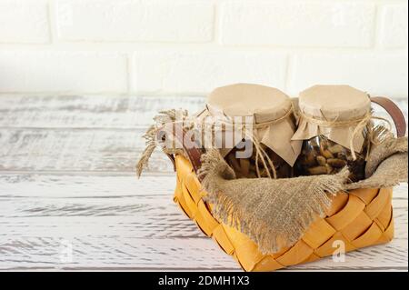 Gläser mit Pilzkonserven in einem Korb. Fermentierte Nahrung auf weißem Hintergrund mit Kopierraum. Stockfoto