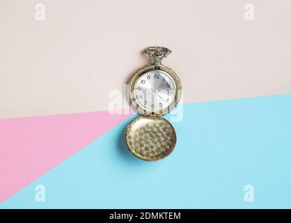 Vintage Taschenuhr auf farbigem pastellfarbenem Hintergrund, Draufsicht, Minimalismus Stockfoto