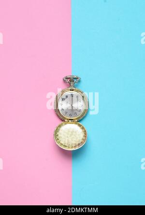 Vintage Taschenuhr auf farbigem pastellfarbenem Hintergrund, Draufsicht, Minimalismus Stockfoto