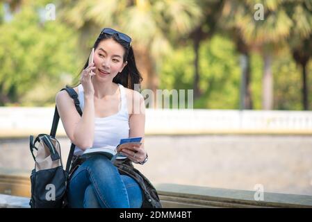 Schöne asiatische tourist Frau lesen der Reiseführer buchen Sie suchen für Touristen Besichtigungen vor Ort. Ferienhäuser Reisen im Sommer. Stockfoto