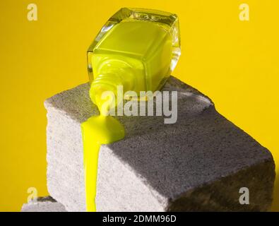 Gelber Nagellack fließt auf grauem Betonstein. Trendfarben Stockfoto