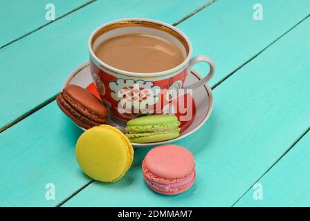 Tasse Kaffee, farbige Makronen auf blauem Holzhintergrund. Stockfoto