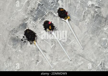 Plastiklöffel mit trockenen Teeblättern auf grauem Betongrund. Stockfoto