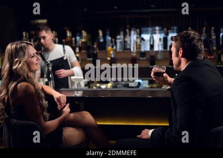 Nette Blondine flirtet mit einem Mann in einer Jacke in einem Nachtclub. Stockfoto