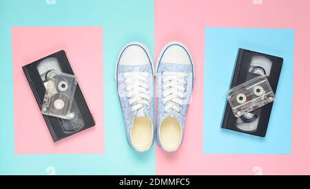 Sneakers, audio cassettes, video cassettes on a pink pastel blue background. Retro attributes from the 80s. Top View Stock Photo