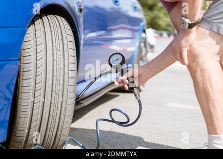 Person Pumpen die Autoräder Reifen mit einem Kompressor Mit Manometer Stockfoto