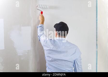 Malen einer Trockenwand durch Malerei Walze und weiße Latexfarbe. Stockfoto