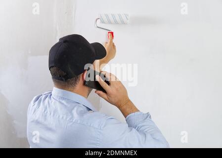 Malen einer Trockenwand durch Malerei Walze und weiße Latexfarbe. Stockfoto