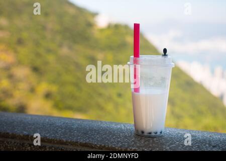 Bubble Tee (Kokosmilch und Perlen) in einem Plastikbecher mit einem Plastikstroh. Nicht umweltfreundlich. Außenaufnahme. Stockfoto
