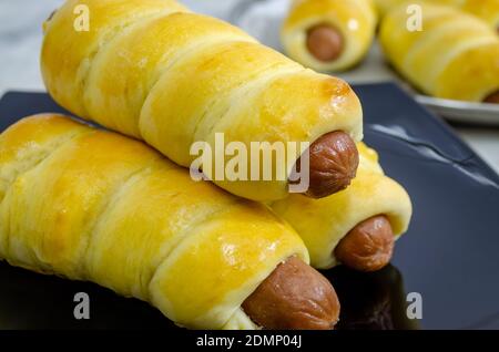 Nahaufnahme von frisch gebackenen und gestapelten Wurstbrötchen auf einem Schwarze Platte Stockfoto