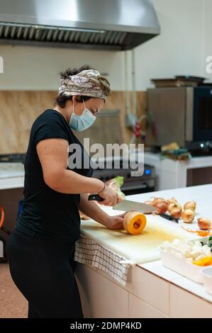 Koch trägt chirurgische Maske Kochen Stockfoto