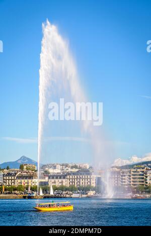 Ein Wasserbus von Mouettes Genevoises überquert die Bucht von Genf mit dem Wasserstrahlbrunnen Jet d'Eau. Stockfoto