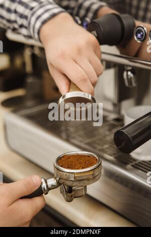 Vertikaler, zugeschnittenes Bild eines Baristas, der Kaffee mithilfe von Sabotagekontakt zubereitet Für Presing gemahlenen Kaffee in portafilter Professionalität Cafe arbeiten Morgen Pause Stockfoto