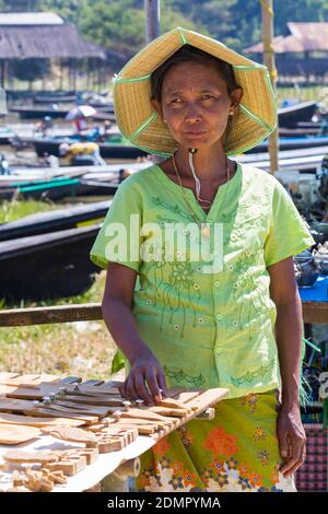 Marktstandhalter, der hölzerne Einzelteile mit konischem Bambushut auf Nam Pan fünf Tagesmarkt, Inle See, Shan Staat, Myanmar (Burma) Asien, Februar verkauft Stockfoto