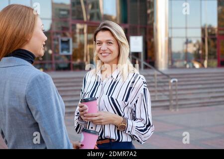 Reife Geschäftsfrau mit Kaffee mit ihrem Kollegen im Freien. Zwei Unternehmerinnen mit Kaffeepause während des Arbeitstages Stockfoto