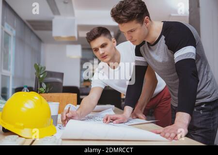 Architekten bei der Arbeit, Engineering-Konzept. Zwei junge männliche Architekten diskutieren Baupläne im Büro, Raum kopieren Stockfoto