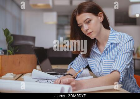Bildung, Erlebniskonzept. Schöne junge Innenarchitektin arbeitet an einem Projekt in ihrem Büro. Kreative Ingenieurin Prüfung buildin Stockfoto
