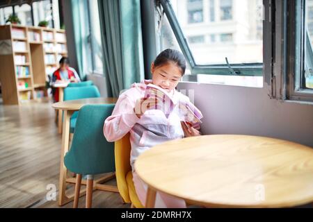 (201217) -- BEIJING, Dec. 17, 2020 (Xinhua) -- A girl reads a book at the bookstore of a relocation site in Zheng'an County of Zunyi City, southwest China's Guizhou Province, Oct. 18, 2020.  The year 2020 is a juncture where China is wrapping up the plan for the 2016-2020 period and preparing for its next master plan.    In 2020, China stepped up efforts to shore up weak links regarding people's livelihoods. A slew of measures has been rolled out to address people's concerns in employment, education, basic medical services, the elderly care, housing, public services, etc. (Xinhua/Liu Xu) Stock Photo