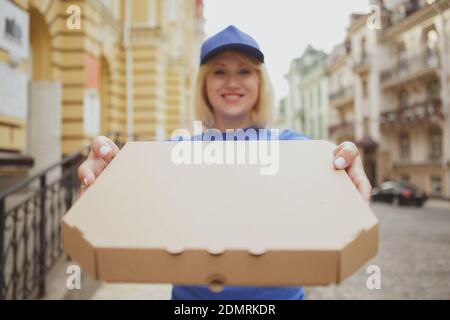 Glückliche weibliche Lieferung Kurier lächelnd, halten aus Karton Pizza-Box an die Kamera, kopieren Raum. Fröhliche Pizza Lieferung Frau mit Karton-Box wi Stockfoto