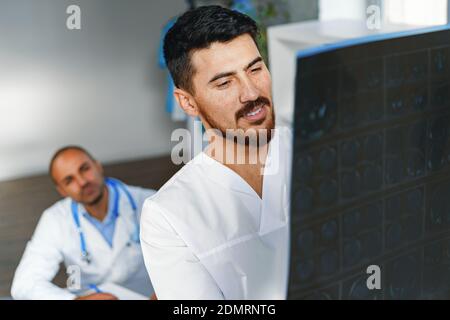 Zwei männliche Ärzte untersuchen MRT-Hirnscans eines Patienten Im Schrank Stockfoto