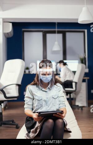 Geschäftsfrau denken über Finanzstrategie mit Tablet-pc tragen Gesichtsmaske gegen covid19. Multiethnisches Geschäftsteam, das während der globalen Pandemie mit covid-19 soziale Distanz respektiert. Stockfoto