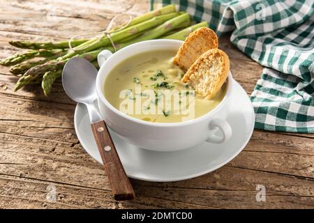Frische grüne Spargelsuppe in Schüssel auf Holztisch. Stockfoto