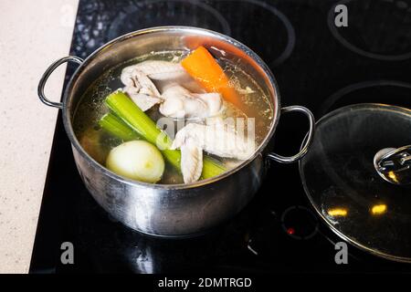 Die obere Ansicht der Hähnchenflügel Brühe ist in Stahl gekocht Stewpot auf Herd zu Hause Küche isoliert auf weißem Hintergrund Stockfoto