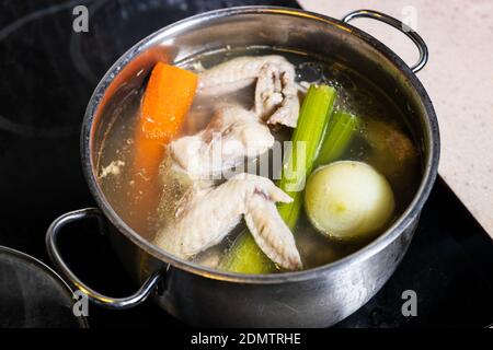 Hähnchenflügel-Suppe wird in Stahlstekpot aus nächster Nähe gekocht Auf Herd zu Hause Küche isoliert auf weißem Hintergrund Stockfoto