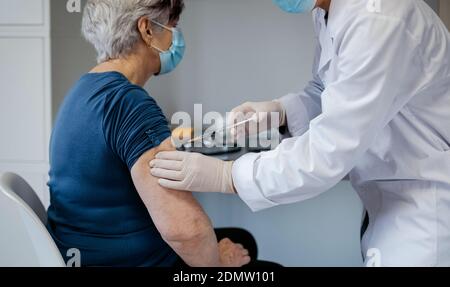 Ältere Frau, die von einer Ärztin gegen Coronavirus geimpft wird Stockfoto