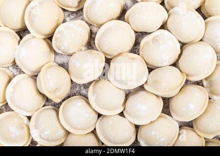 Draufsicht auf viele gefrorene Pelmeni (russische Knödel gefüllt mit Hackfleisch) auf Holzbrett Stockfoto