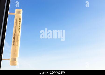 Outdoor-Thermometer auf Home-Fenster durch Sonnenaufgangsshows beleuchtet Null Grad celsius und blauer Himmel auf dem Hintergrund auf sonnig Wintermorgen (konzentrieren Sie sich auf die ther Stockfoto