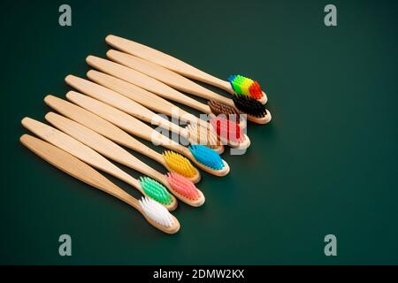 Ein Set umweltfreundlicher antibakterieller Zahnbürsten aus Bambusholz auf dunkelgrünem Hintergrund. Umwelttrends. Stockfoto