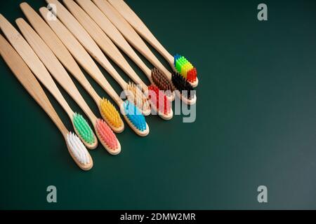 Ein Set umweltfreundlicher antibakterieller Zahnbürsten aus Bambusholz auf dunkelgrünem Hintergrund. Umwelttrends. Stockfoto