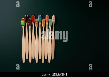 Ein Set umweltfreundlicher antibakterieller Zahnbürsten aus Bambusholz auf dunkelgrünem Hintergrund. Umwelttrends. Stockfoto