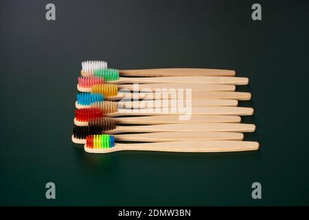 Ein Set umweltfreundlicher antibakterieller Zahnbürsten aus Bambusholz auf dunkelgrünem Hintergrund. Umwelttrends. Stockfoto