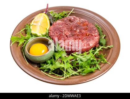 Eigelb in Schüssel und Steak Tartare (Rohes Hackfleisch) Auf frischem Grün auf brauner Platte isoliert auf weißem Hintergrund Stockfoto