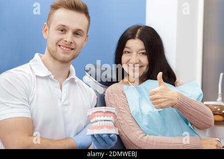 Absolut gesund! Ältere Frau lächelt glücklich zeigt Daumen nach oben in der Zahnklinik ihr Zahnarzt lächelt auf die Kamera halten Zähne Schimmel Beruf Stockfoto