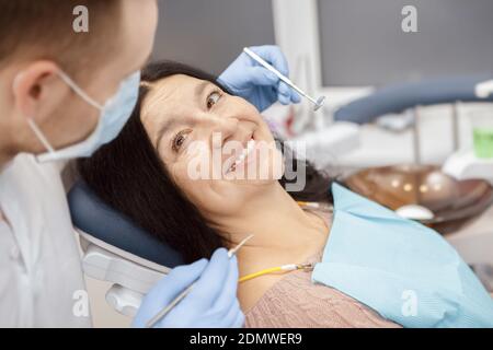 In guten Händen. Glückliche ältere Frau sitzt in einem Zahnstuhl lächelnd zu ihrem Zahnarzt während der Untersuchung in der Zahnklinik Vertrauen Kommunikation Gesundheitsversorgung Stockfoto