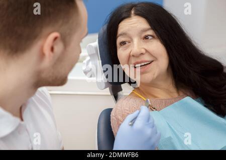 Getting his advice. Senior female patient talking to her dentist at the dental clinic checkup examination healthcare helpful help questions consultati Stockfoto