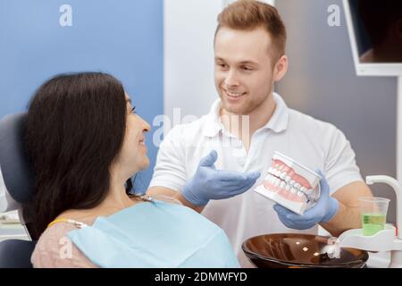 Zahnpflege. Schöner junger professioneller Zahnarzt erklärt seinen älteren Patienten, wie man nach Zähnen zu pflegen zeigt einen Zahnschimmel arbeiten in der Zahnklinik PR Stockfoto