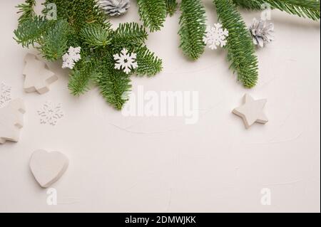 Weihnachtliche Komposition mit grünen Tannenzweigen und weißen Holzdekorationen Von Sternen und Herzen auf weißem Holzhintergrund mit Copyspace Stockfoto